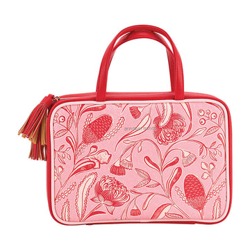 Pink floral-patterned handbag with red handle on a white background.