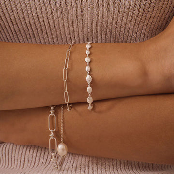 A silver bracelet with shells linked together.