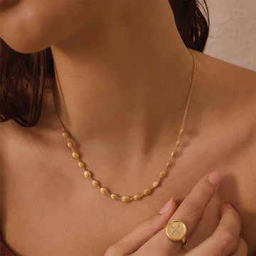 A gold necklace made of shells linked together.