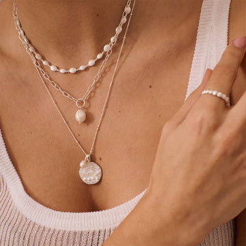 A silver necklace made from shells linked together.