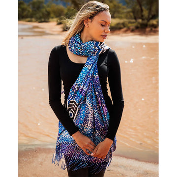 Front view of a model wearing black clothing with a blue scarf printed with artwork by Alma Granites.
