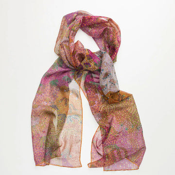 A sheer scarf printed with artwork by Sandra Pula tied in a loose knot.