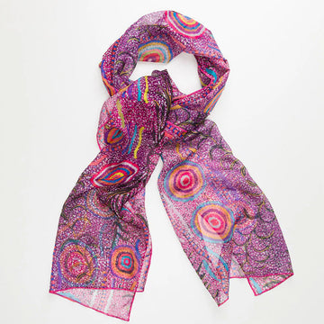 A pink sheer scarf printed with artwork by Jeanie Ross in a loose knot.