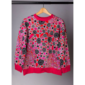 A jumper in red and black featuring artwork by Bess Poulson hanging off a coat hanger.