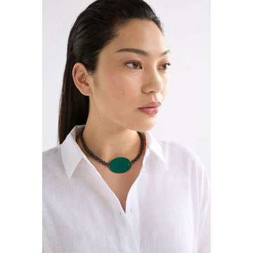 A necklace with a gunmetal grey chain and an oval shaped green pendant in the middle.