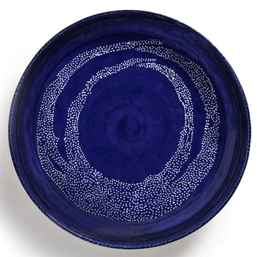 Top down view of a large ceramic serving bowl in dark blue with a white dot pattern.