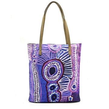 A tote bag printed with artwork by Murdie Morris in purple with brown straps.