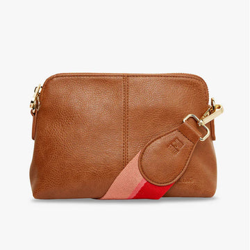 A rectangle shaped cross body bag in tan with a wide red and pink striped strap.