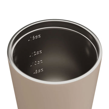 A stainless steel reusable coffee cup in a light brown with a black lid.