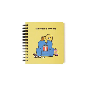 A spiral notebook with an illustration of a cartoon bear on a couch.