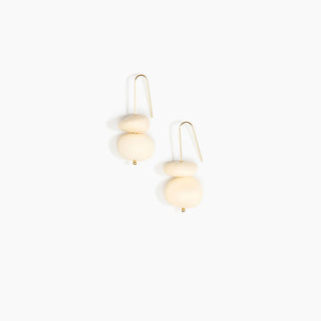 Pair of earrings with cream resin beads on a white background.
