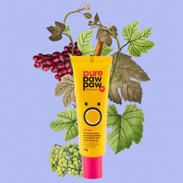 Yellow tube of pure paw paw ointment with grapes and leaves on a blue background.