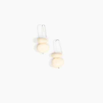 Pair of earrings with beige resin beads on a white background.