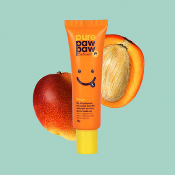 Orange tube of 'pure paw paw' ointment with a smiley face on a light blue background with mangoes. 