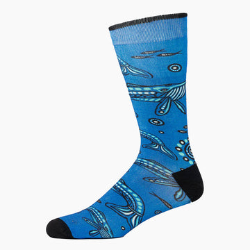 A blue sock with a black heel and toe and illustrated with whales.