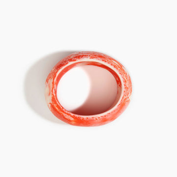 Orange and white bangle on a light gray background.