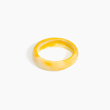 Yellow bangle made from resin on a white background.