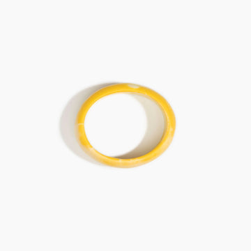 Yellow bangle made from resin on a white background.