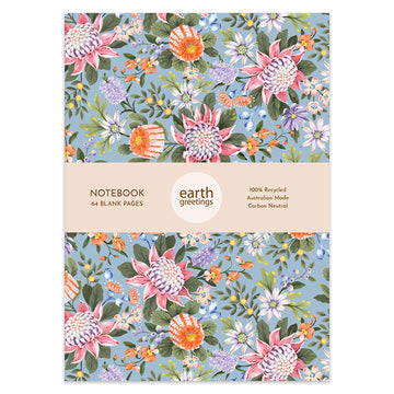 A notebook cover illustrated with waratah and banksia flowers in pink and orange on a blue background. There is a product information sleeve around the middle.