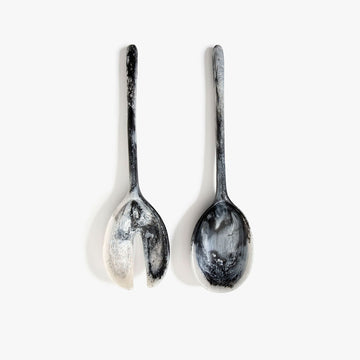 Two marbled black and white salad servers on a white background.