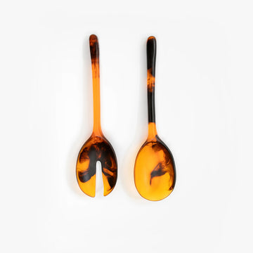 Two tortoiseshell patterned salad servers on a white background.