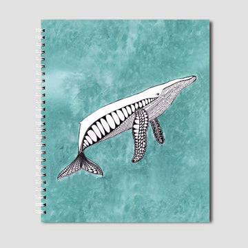 A spiral notebook in blue with an illustration of a black and white whale.