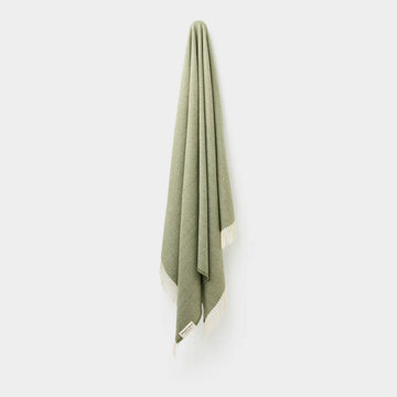 Green throw with white border on a white background.
