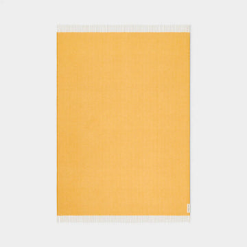 Yellow throw with white fringe on a light gray background.
