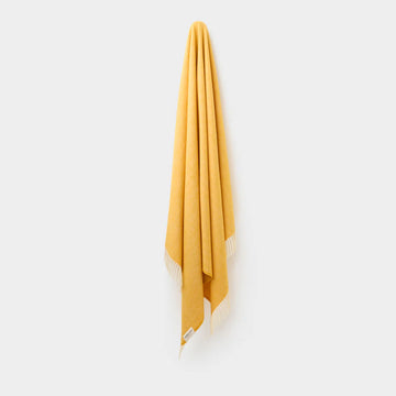 Yellow throw with white fringe on a light gray background.