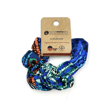 A scrunchie printed with blue and green artwork attached to a brown card.
