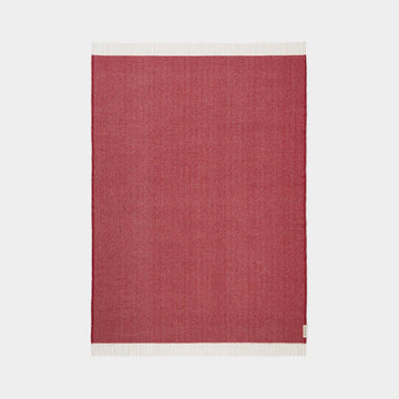 Red throw with white border on a light gray background.