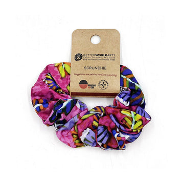 A scrunchie printed with pink, yellow and blue artwork attached to a brown card.