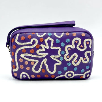 A purple toiletry bag embroidered with white wavy lines and colourful dots.