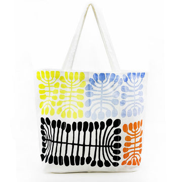 A large white tote bag printed with artwork of yellow, blue, black and orange motifs.