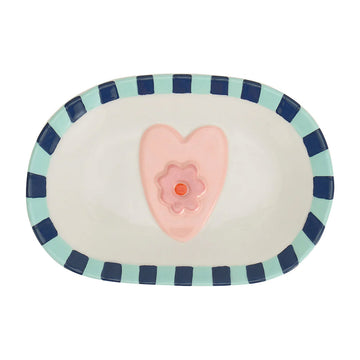 An oval shaped ceramic plate with a striped border and a pink heart and flower in the middle.
