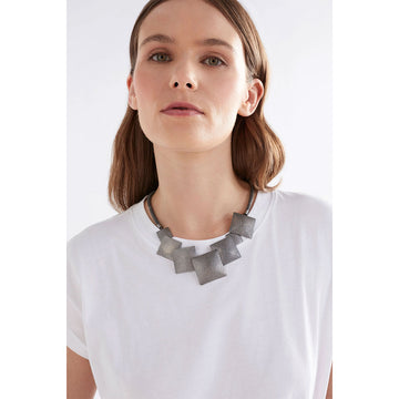 A silver mesh chain necklace with seven different sized squares on the front.