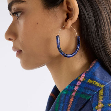 Pair of blue tortoiseshell hoop earrings on a white background