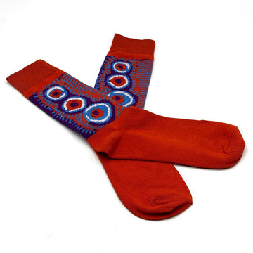 A pair of red socks overlapping each other and printed with artwork by Murdie Morris on the ankle part of the sock.