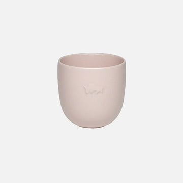 Pink ceramic cup on a light gray background.