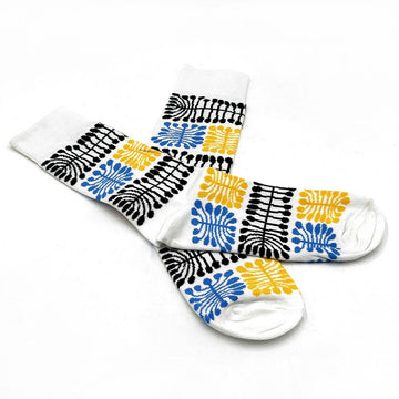 A pair of white socks overlapping each other and printed with black, blue and yellow motifs.