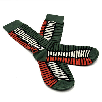 A pair of dark green socks printed with artwork by Kurun Warun are overlapping each other.