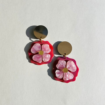 A pair of drop stud earrings with flowers attached to large gold circles.