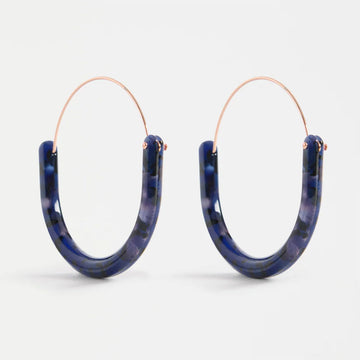 Pair of blue tortoiseshell hoop earrings on a white background