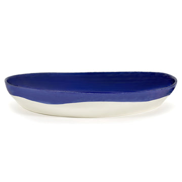Top down view of a large ceramic serving bowl in dark blue with a white dot pattern.