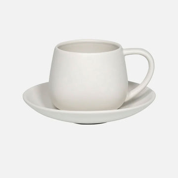 White ceramic cup and saucer on a light gray background.
