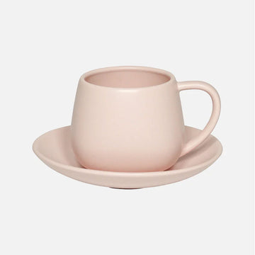 Pink ceramic cup and saucer set on a light gray background.