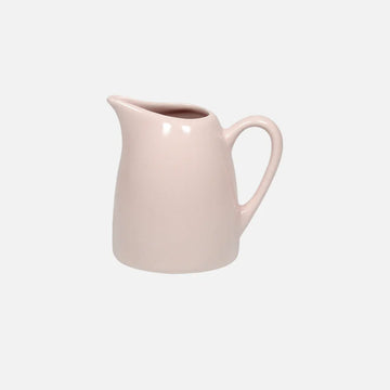 Pink ceramic pitcher on a light gray background.