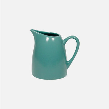Teal ceramic pitcher on a white background.