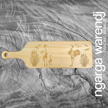 A wooden board with a handle and etched with a design of brolgas. 