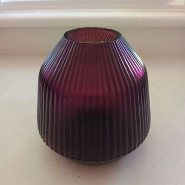 Purple ribbed glass vase on a light background.